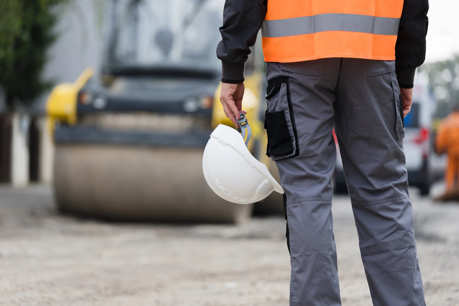 Deux ouvriers du BTP en équipements de protection individuelle haute visibilité examinent des documents techniques sur un chantier extérieur