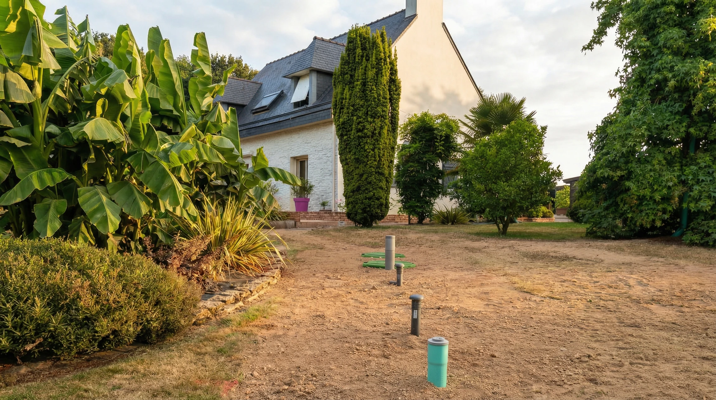Terrain r&eacute;sidentiel vacant avec pelouse clairsem&eacute;e et zones de terre nue, entour&eacute; de cl&ocirc;tures en bois