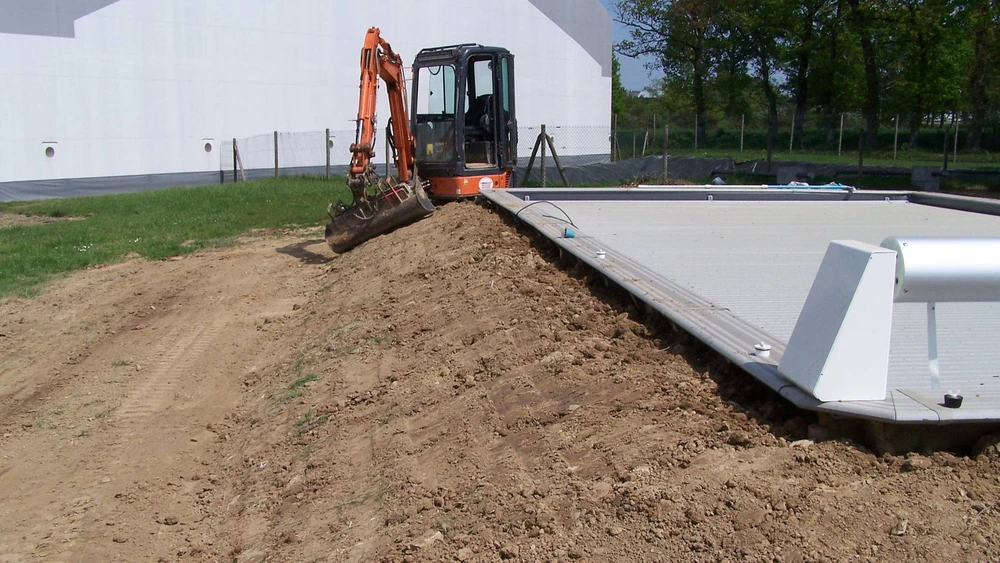 Chantier extérieur résidentiel avec terrain en préparation devant maison moderne à bardage bois
